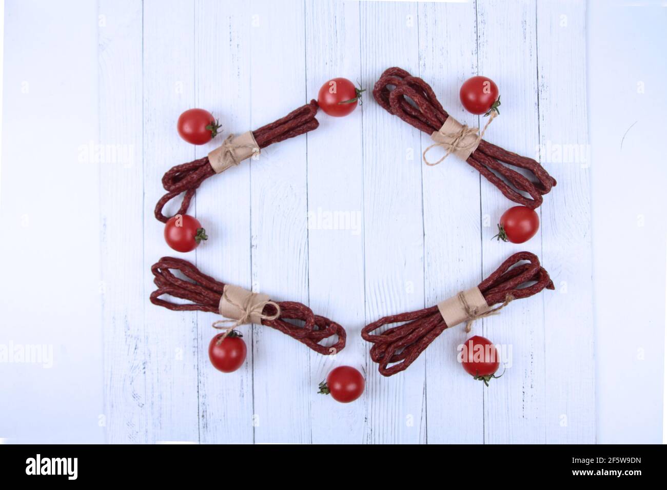 Telaio di kabanos o cabanossi - tradizionale polacca sottile salsiccia secca affumicata fatta di manzo ed erbe e ciliegia tomatos piatto. L'immagine contiene una copia spa Foto Stock