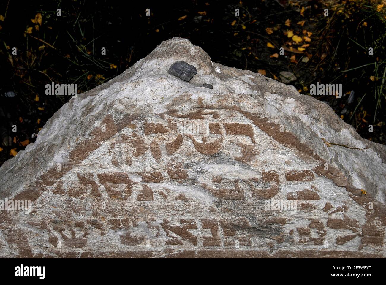 Ciottoli o pietre lasciate in cima a questa antica lapide, secondo la tradizione e l'abitudine ebraica, indica che qualcuno ha visitato la tomba nel vecchio cimitero ebraico di Josefov, il quartiere ebraico di Praga, capitale della Repubblica Ceca. La lapide, con un'iscrizione ebraica scolpita in rilievo, è tra circa 12,000 crammed in quasi 350 anni nello spazio murato del centro della città, con circa 100,000 abitanti dell'ex ghetto che giacciono in un massimo di 12 strati al di sotto di essi. La prima lapide risale al 1439 e l'ultima interazione risale al 1787. Foto Stock