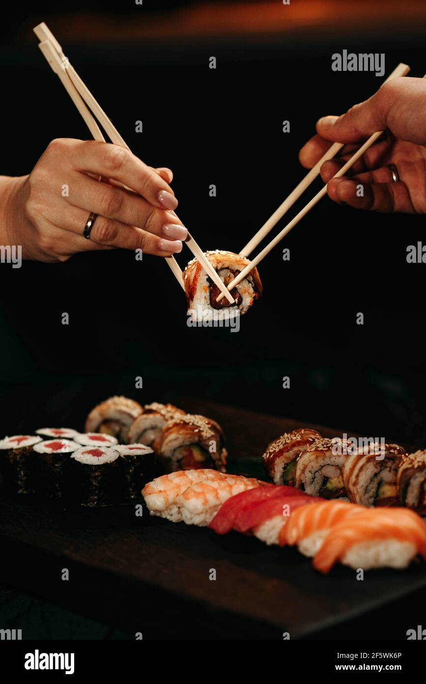 L'uomo e la donna raccolse il sushi con i chopsticks al allo stesso tempo Foto Stock