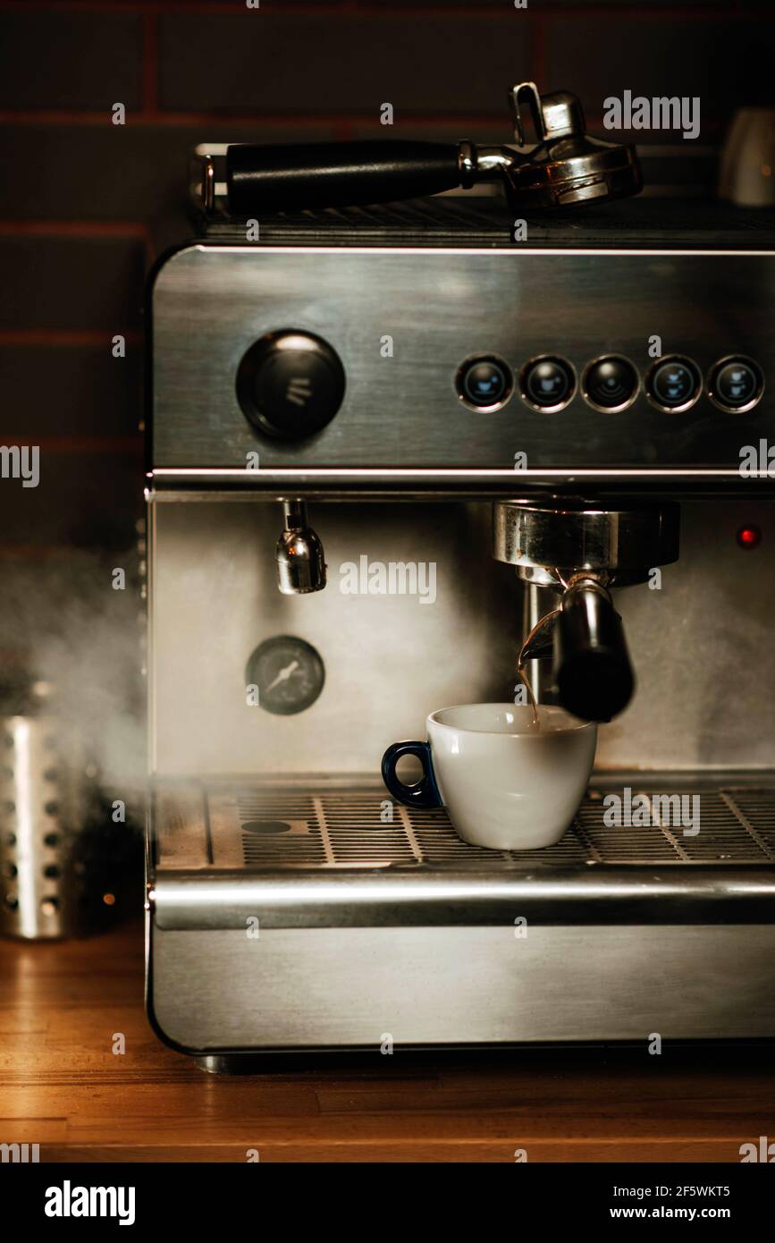 Tazza bianca sul vassoio antigoccia con vapore proveniente da il vaporizzatore Foto Stock