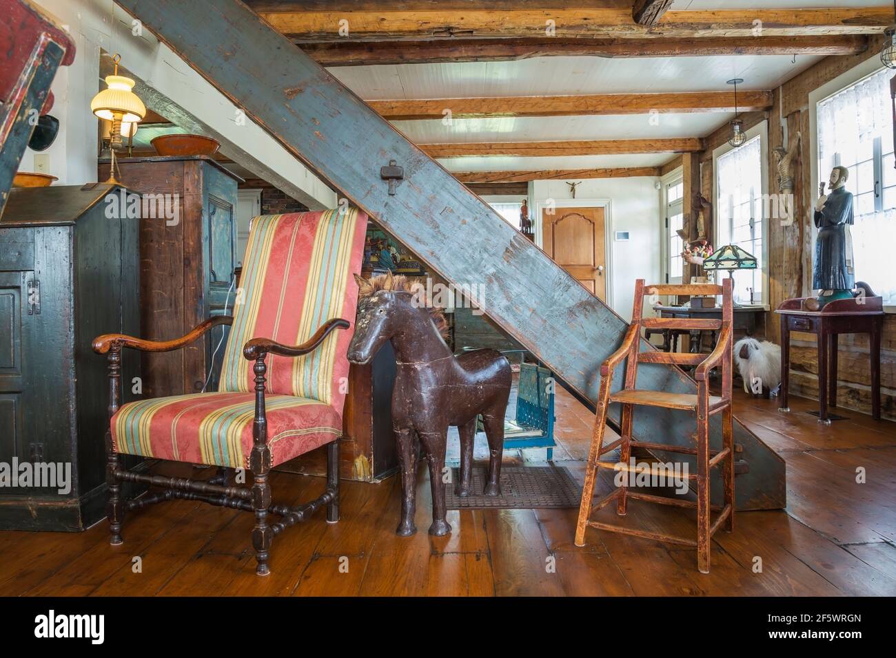 Poltroncina in legno antico rivestita a strisce rosse, blu acqua e gialle, seggiolone con seduta in legno massiccio, scultura a cavallo in legno nel soggiorno Foto Stock