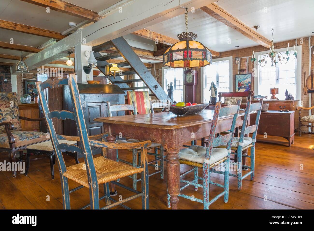 Tavolo da pranzo in legno di pino colorato marrone antico con dipinti in difficoltà sedie a sdraio in legno blu in sala da pranzo con ampia pavimenti in legno di pino Foto Stock