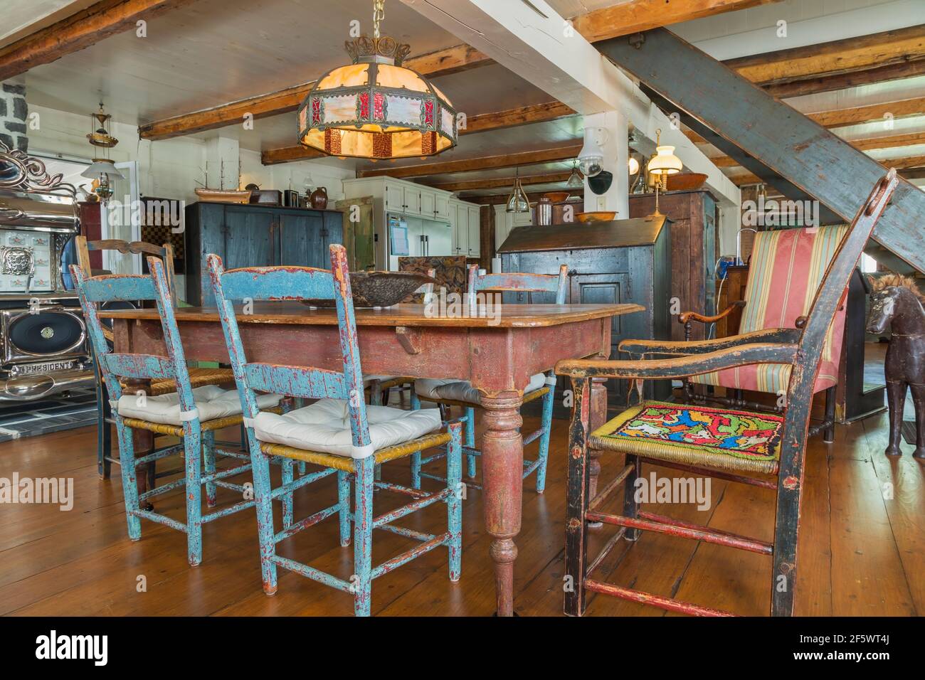 Tavolo da pranzo in legno di pino colorato marrone antico con dipinti in difficoltà sedie a sdraio in legno blu in sala da pranzo con ampia pavimenti in legno di pino Foto Stock