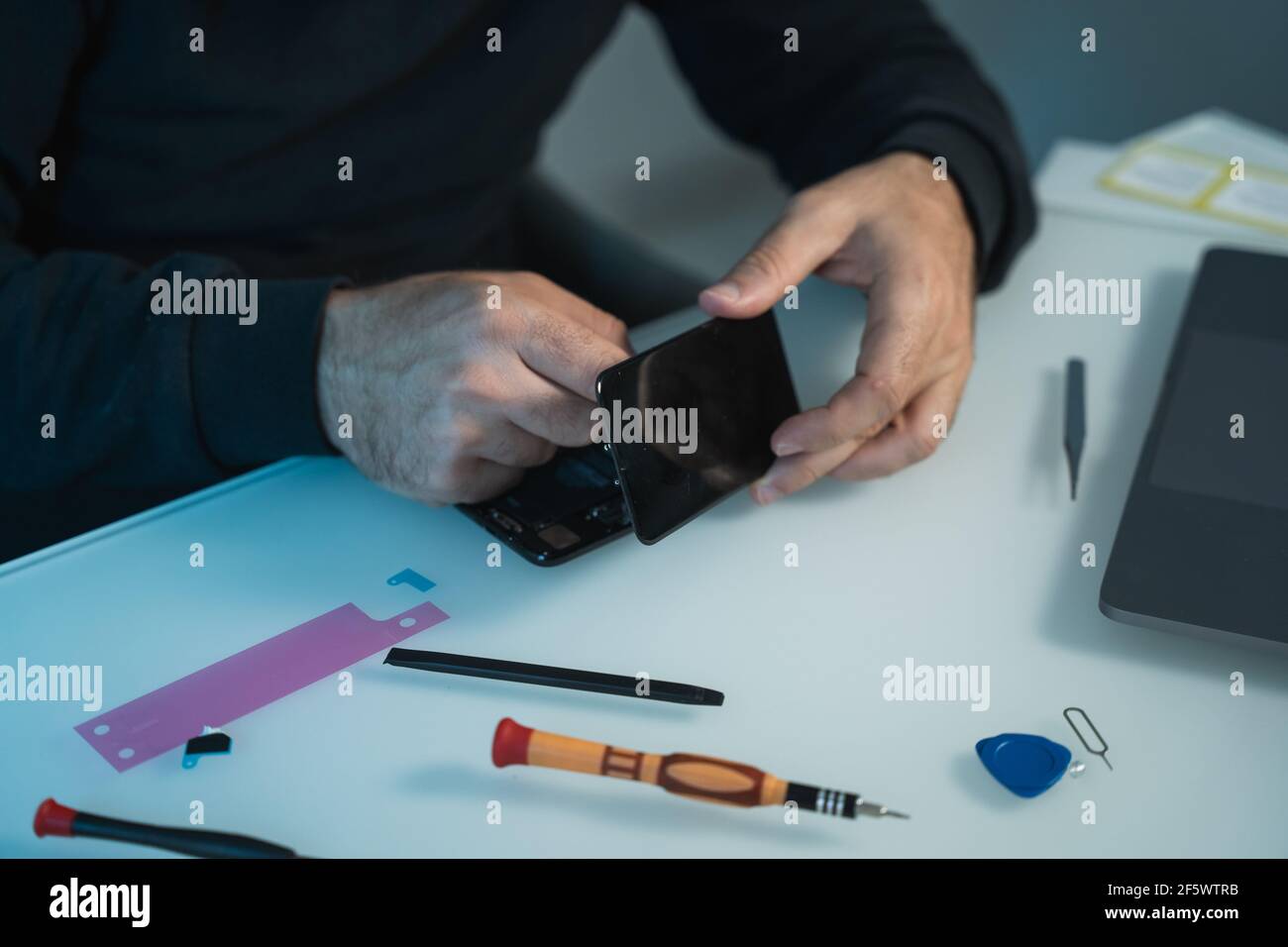 Tecnico o tecnico che si appresta a riparare e sostituire il nuovo smartphone preparazione dello schermo alla scrivania Foto Stock