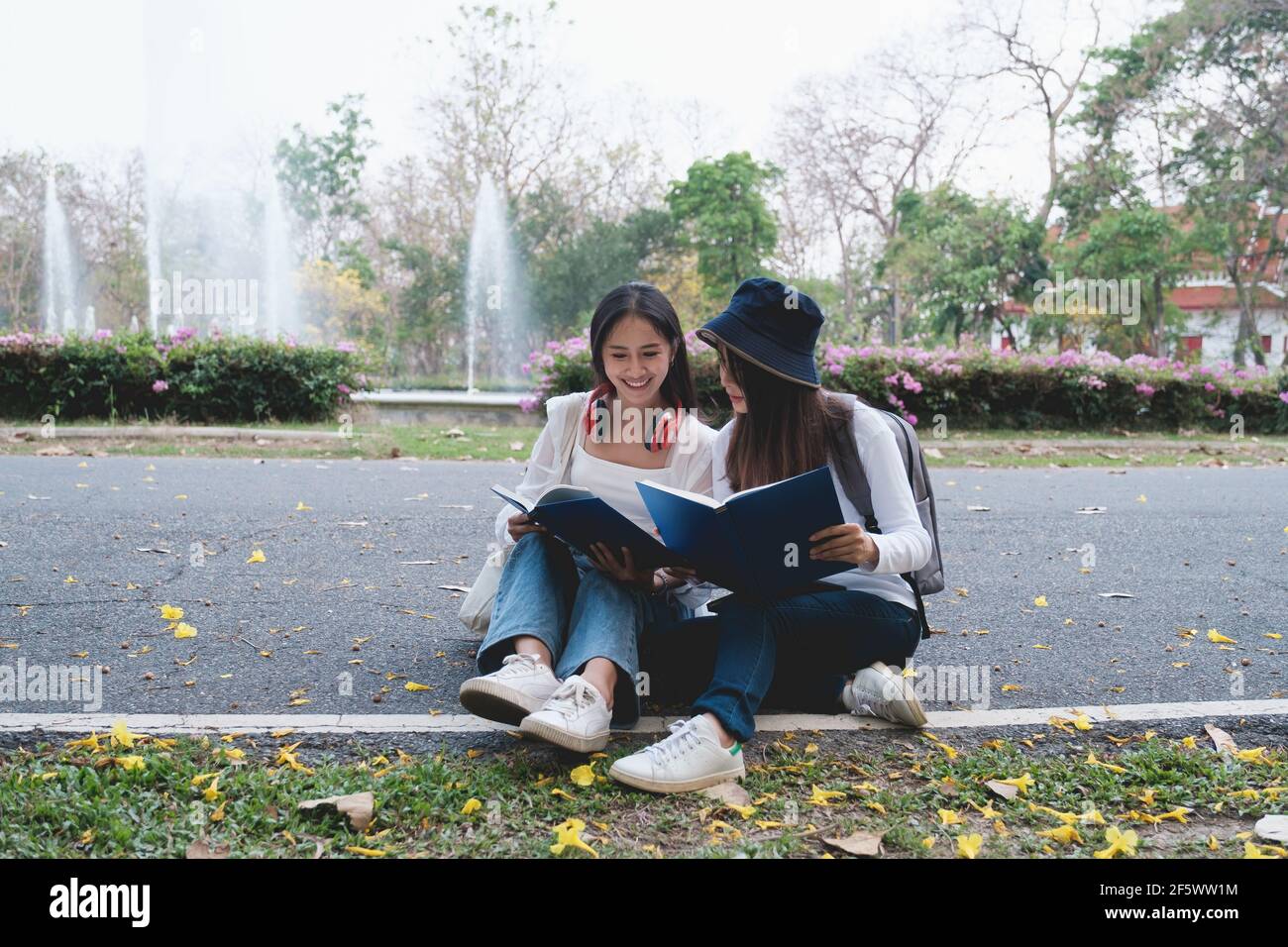 Due studenti si trovano all'università durante la lettura di un libro e della comunicazione. Studio, istruzione, università, università, concetto di laurea. Foto Stock