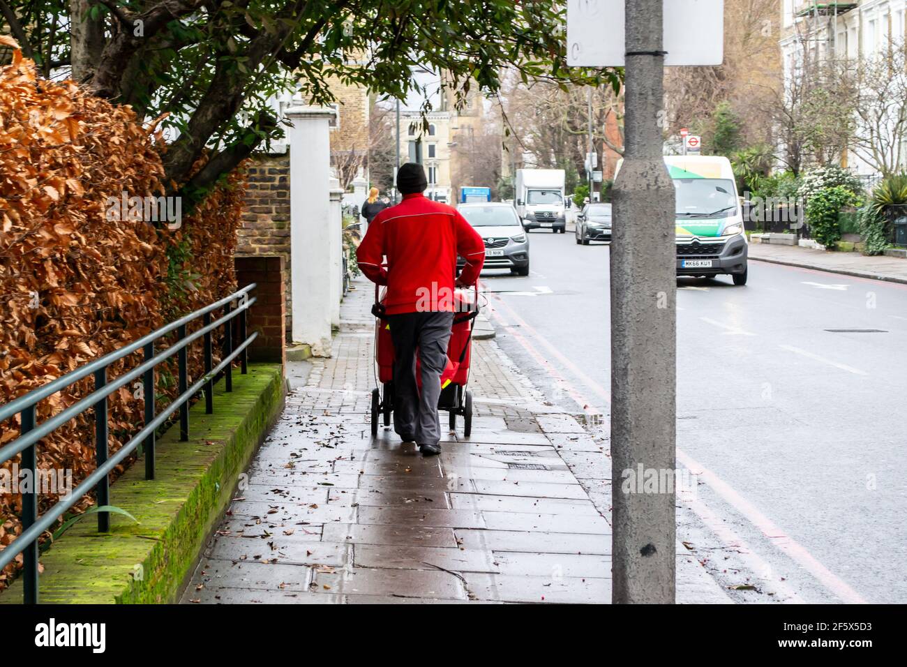 CHELSEA, LONDRA, INGHILTERRA - 17 febbraio 2021: Assistente postale Royal Mail che spinge un carrello a Chelsea Foto Stock
