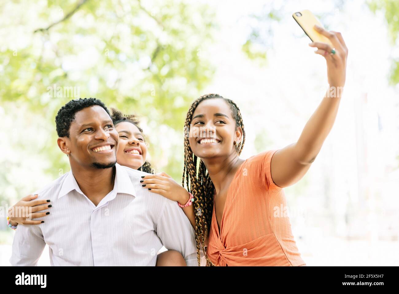 Famiglia che prende un selfie con un telefono cellulare al parco. Foto Stock