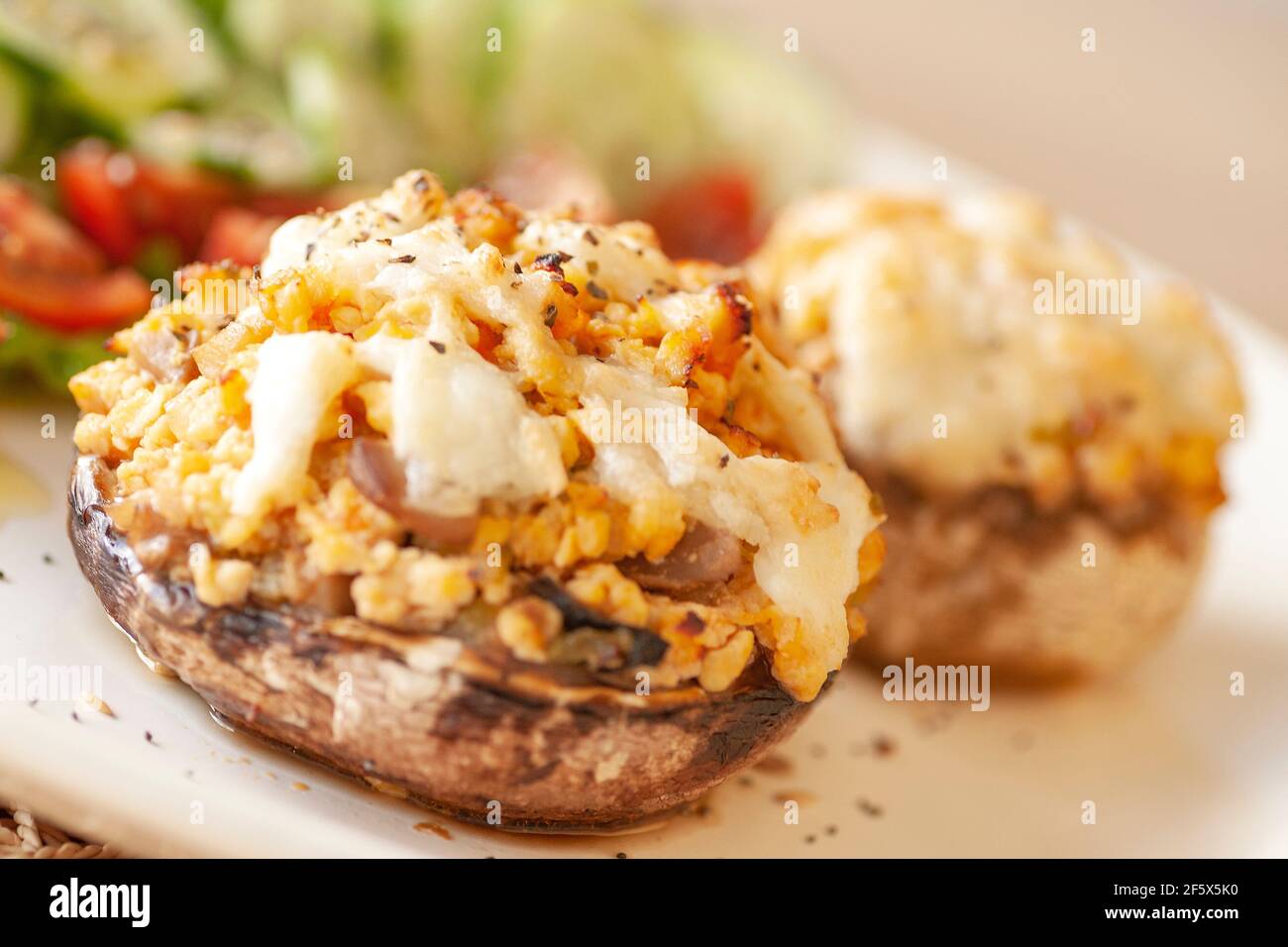 Cucina mediterranea. Funghi farciti con formaggio, insalata, pomodoro, cetriolo, limone. Foto Stock