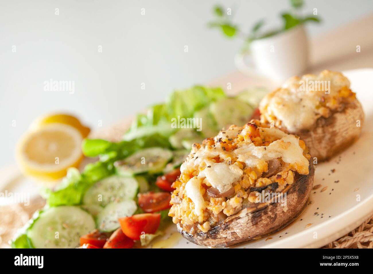 Cucina mediterranea. Funghi farciti con formaggio, insalata, pomodoro, cetriolo, limone. Foto Stock