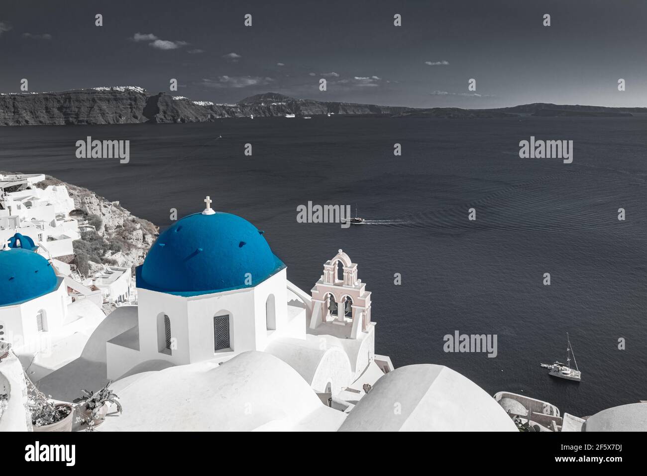 Immagine a colori selettiva, colore blu con processo in bianco e nero. Vista di Oia a Santorini, caldera e cupola blu della chiesa. Viaggio idilliaco e stimolante Foto Stock