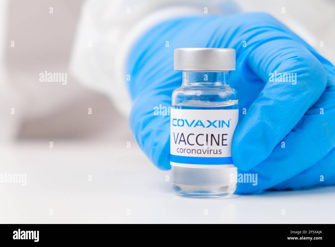 Vaccino di Covaxin contro SARS-Cov-2, coronavirus o Covid-19 messo sul tavolo da un medico nei guanti di gomma. Foto Stock