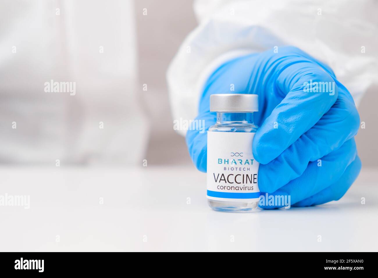 Vaccino Bharat biotech contro SARS-Cov-2, coronavirus o Covid-19 messo sul tavolo da un medico nei guanti di gomma. Foto Stock