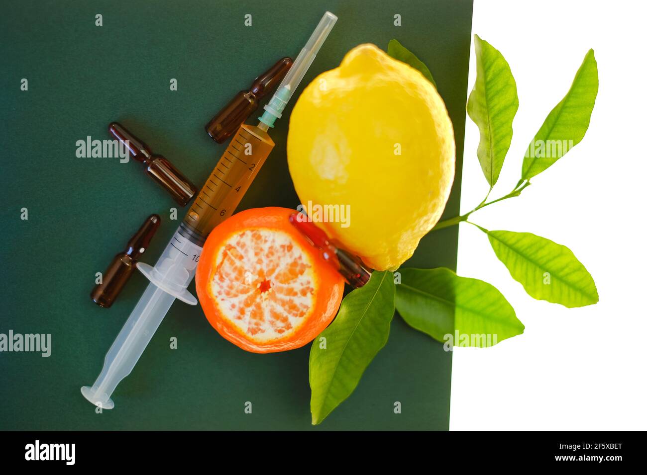 Siero di vitamina C. con fiale di vetro di vitamina C. siringa con soluzione iniettabile e limoni di frutta su fondo verde isolati su fondo bianco Foto Stock
