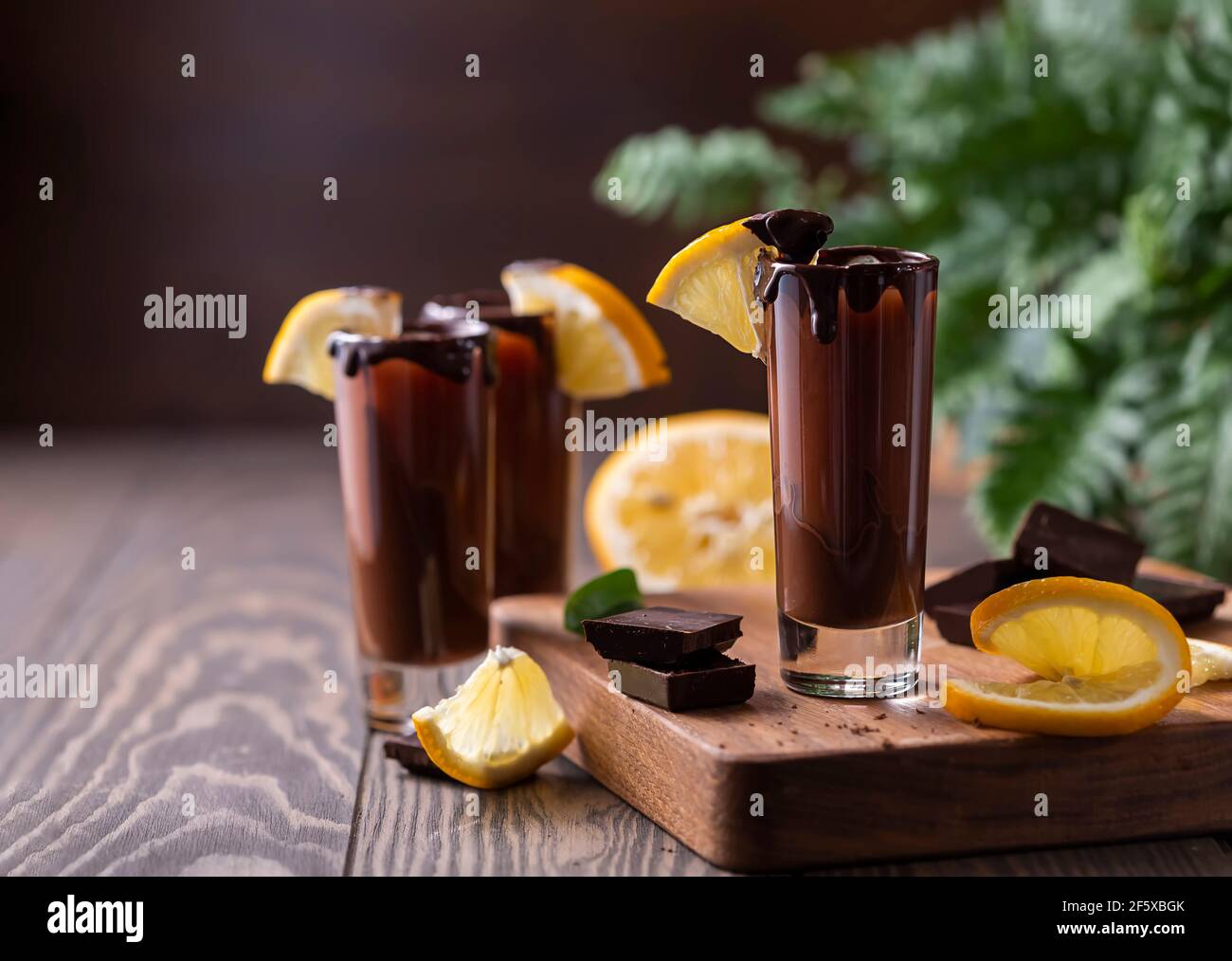 Cocktail in bicchierino con cioccolato, liquore alla crema, arance fresche su sfondo scuro. Festa fatta in casa con bevande a base di shot. Menu bar, ricette. Primo piano, selec Foto Stock