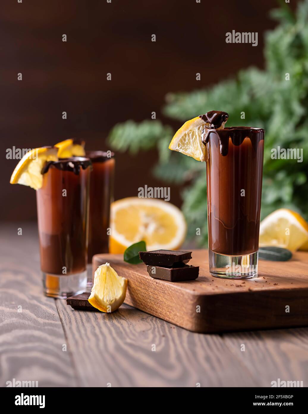 Cocktail in bicchierino con cioccolato, liquore alla crema, arance fresche su sfondo scuro. Festa fatta in casa con bevande a base di shot. Menu bar, ricette. Primo piano, selec Foto Stock