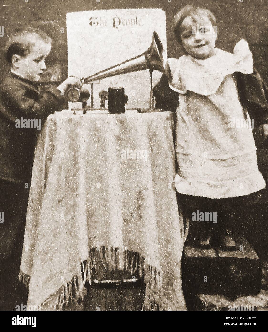 1910 - una foto d'epoca di bambini inglesi edoardiani sconosciuti che usano un raro fonografo in miniatura progettato per essere utilizzato nelle scuole e nei vivai come giocattolo di lavoro. Foto Stock