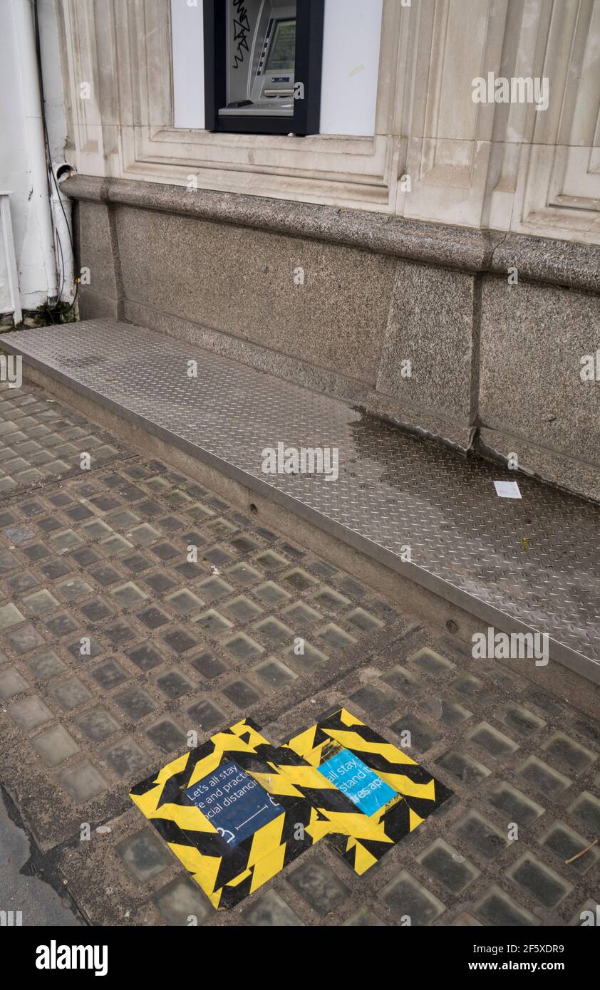 Un segnale per l'allontanamento sociale presso una cassa di una banca durante il blocco per curvare la diffusione della pandemia di Coronavirus a Londra, Inghilterra. Foto Stock