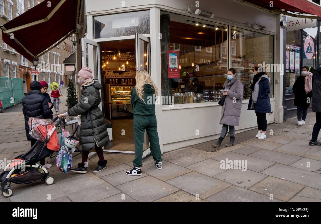 La gente aspetta in fila per entrare in un supermercato che indossa maschere e mantenere la distanza sociale a causa delle restrizioni pandemiche di Coronavirus a Londra, Inghilterra. Foto Stock