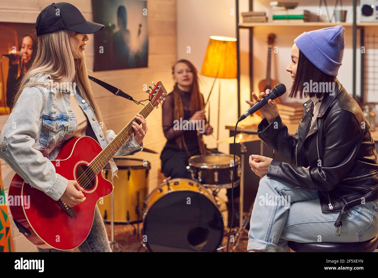 Gruppo di giovani donne che cantano e suonano strumenti musicali durante prova in studio Foto Stock