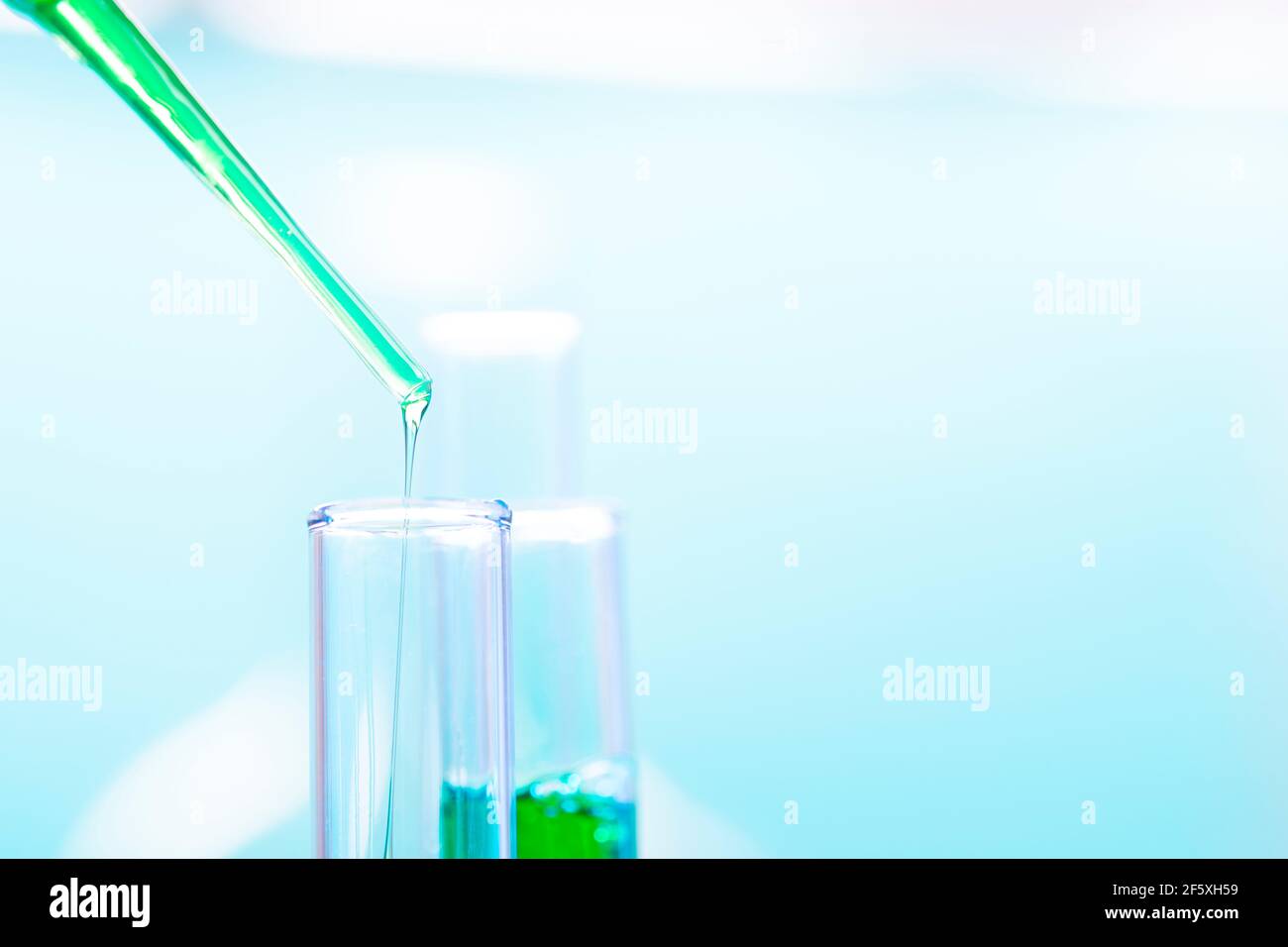 Provette per analisi chimiche e pipetta con liquido verde da vicino in un laboratorio chimico. Foto Stock
