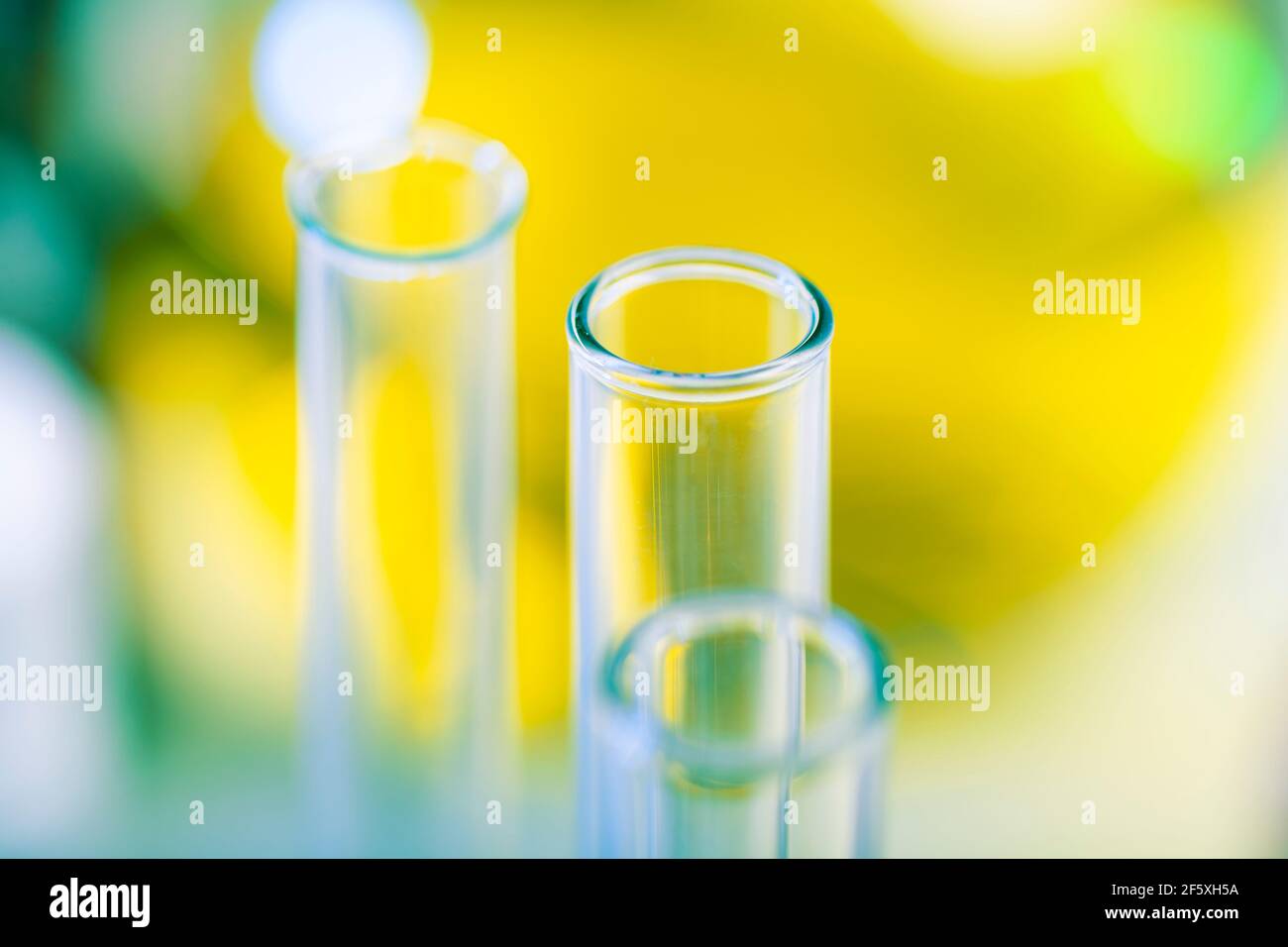 Provette per analisi chimiche sullo sfondo di un matraccio chimico di vetro grande con liquido giallo. Foto Stock