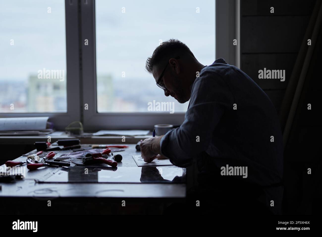 Silhouette di un artista operaio o di un designer industriale professionale in uno studio. Luogo di lavoro di un professionista che fa la fabbricazione o che fa qualcosa. Foto di alta qualità Foto Stock