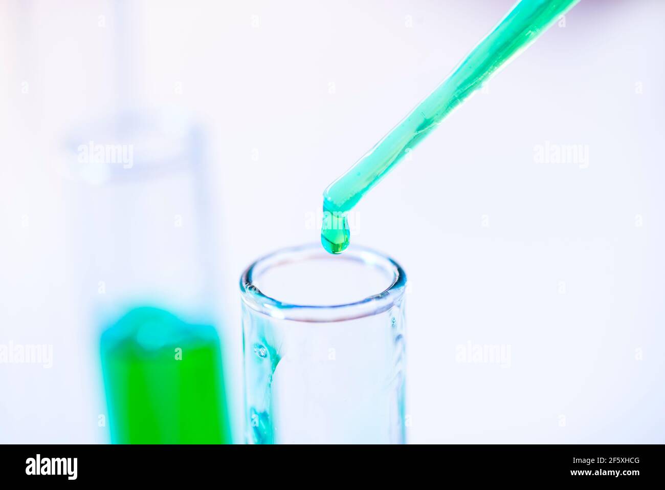 Provette per analisi chimiche e pipetta con liquido verde da vicino in un laboratorio chimico. Foto Stock