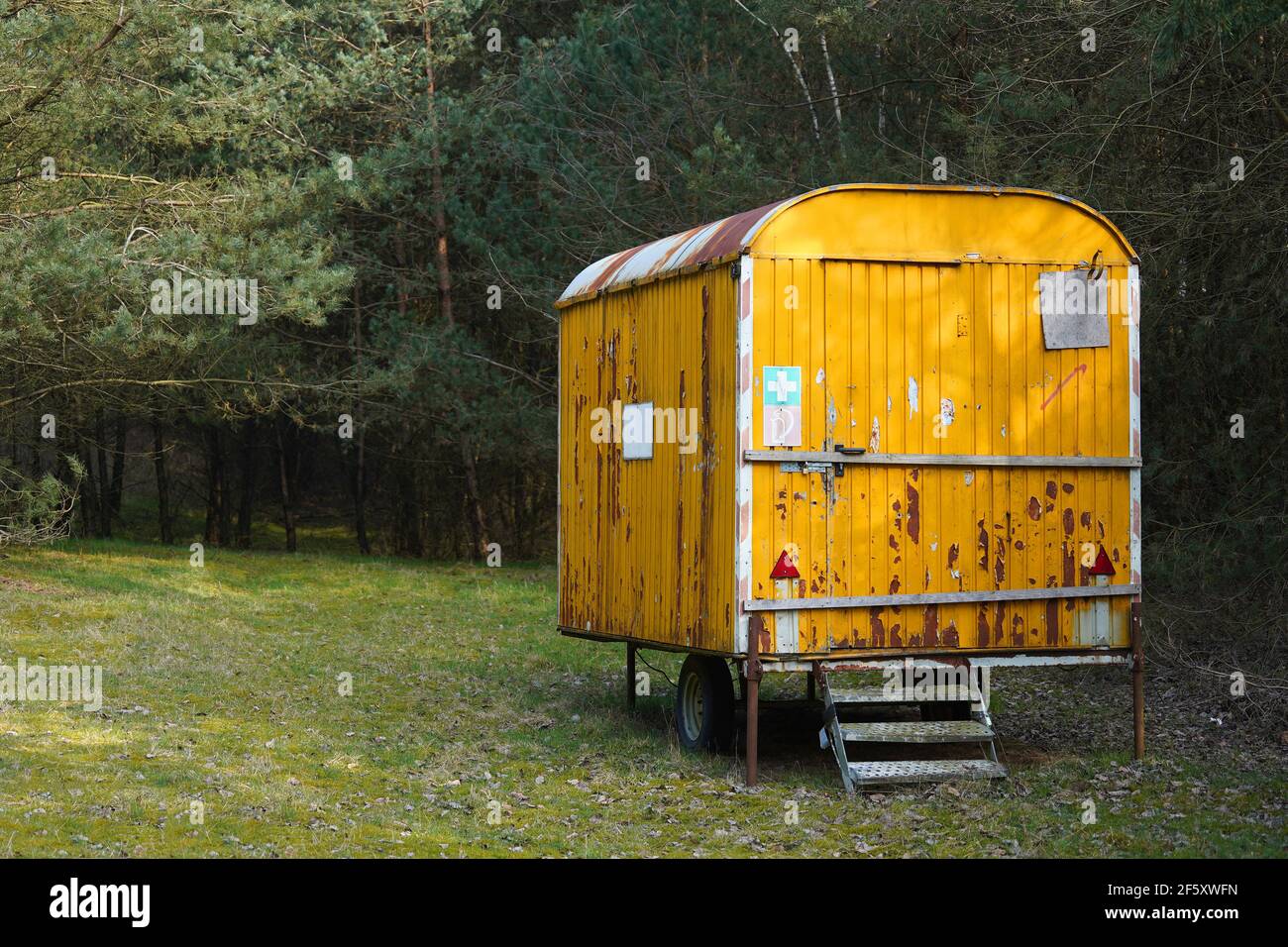 Old giallo ruggine costruzione camper, rimorchio, furgone o vagone nella foresta. Alloggio temporaneo per i lavoratori forestali . Foto Stock