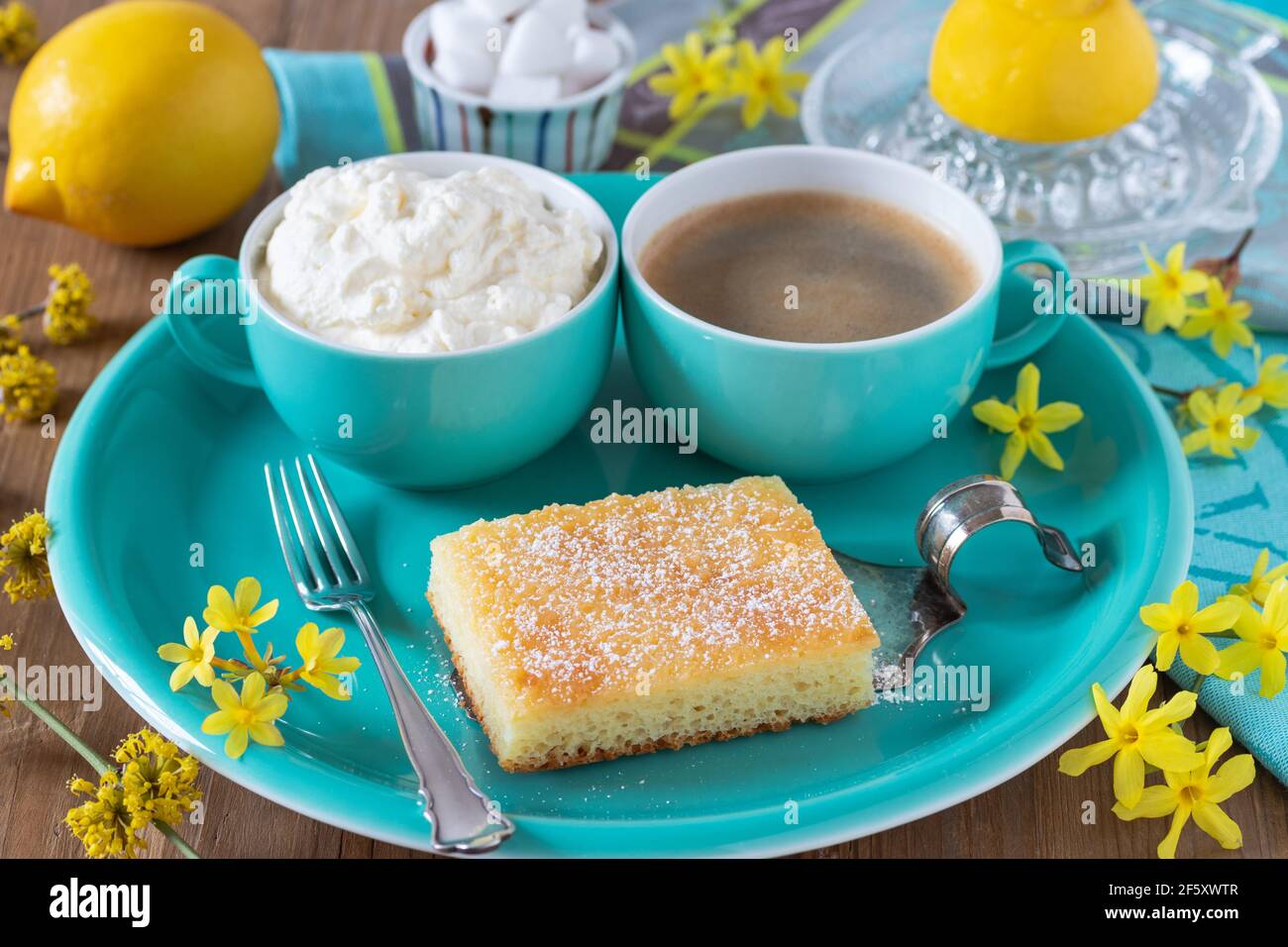 pezzo di torta al limone sul piatto, tazza di caffè e panna montata Foto Stock