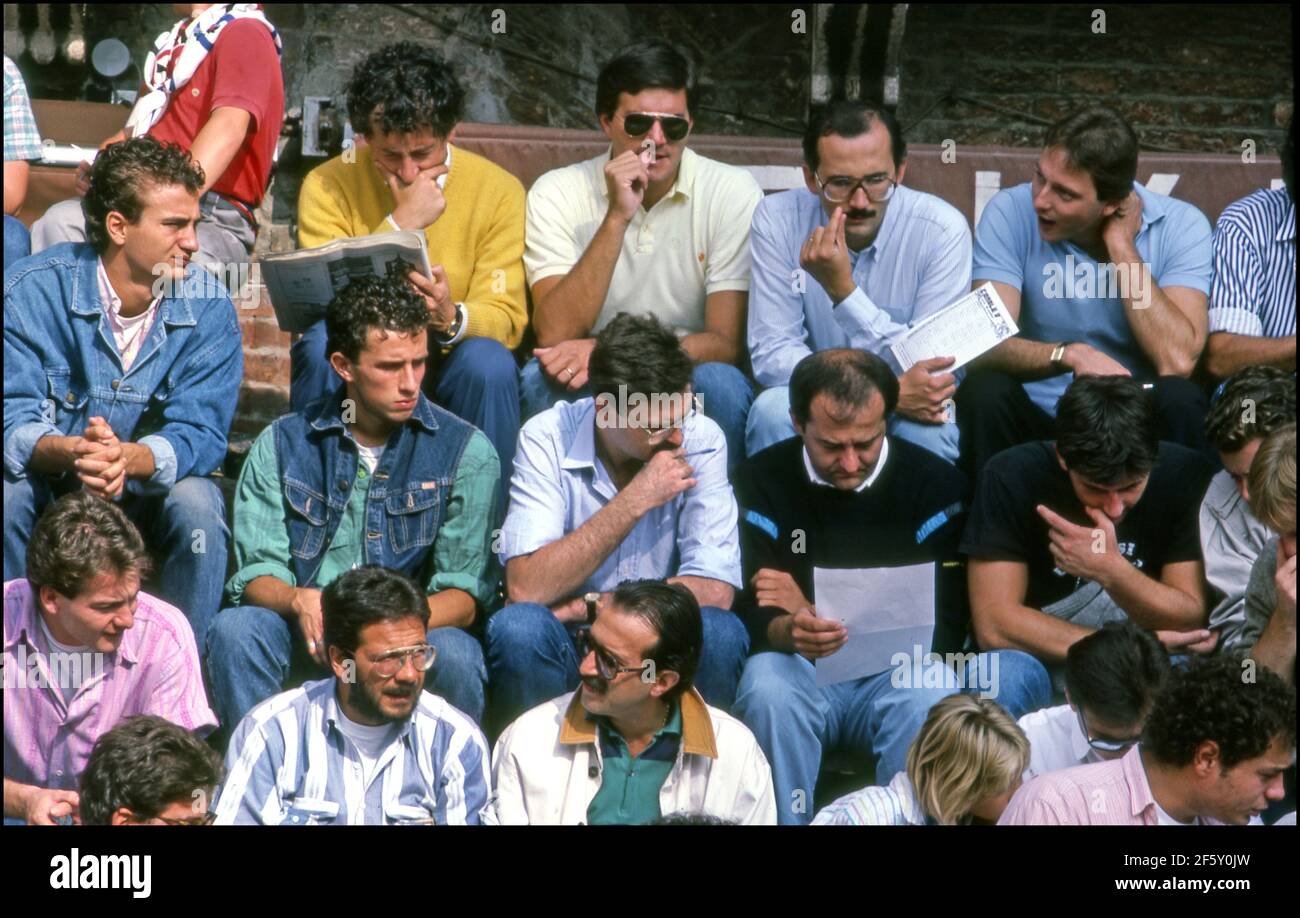 Uomini italiani che guardano là le schede di scommessa per la corsa dei cavalli poco prima del Palio a Siena, Italia Foto Stock