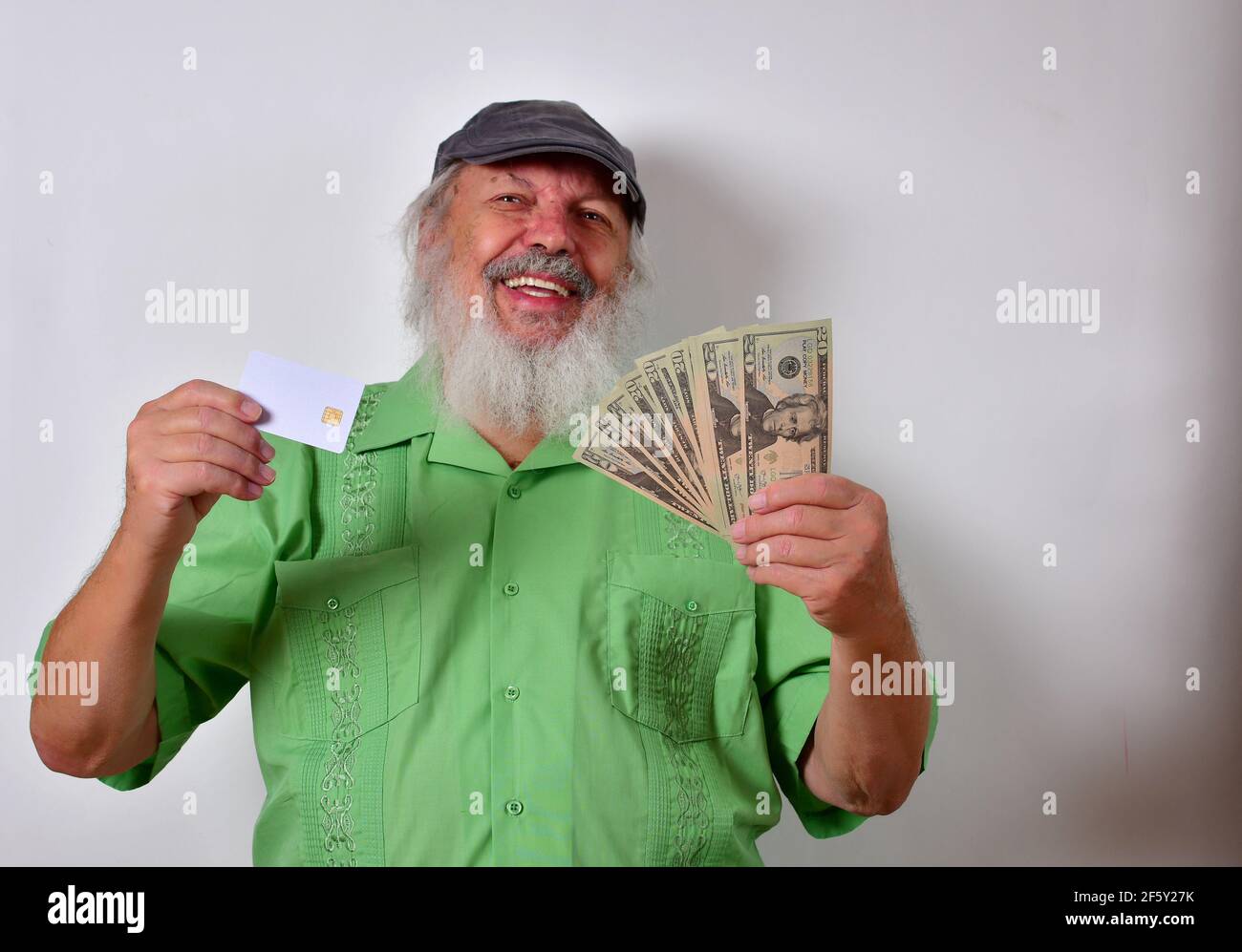 Vecchio maschio americano con camicia verde che ci tiene dollari e. una carta di credito Foto Stock