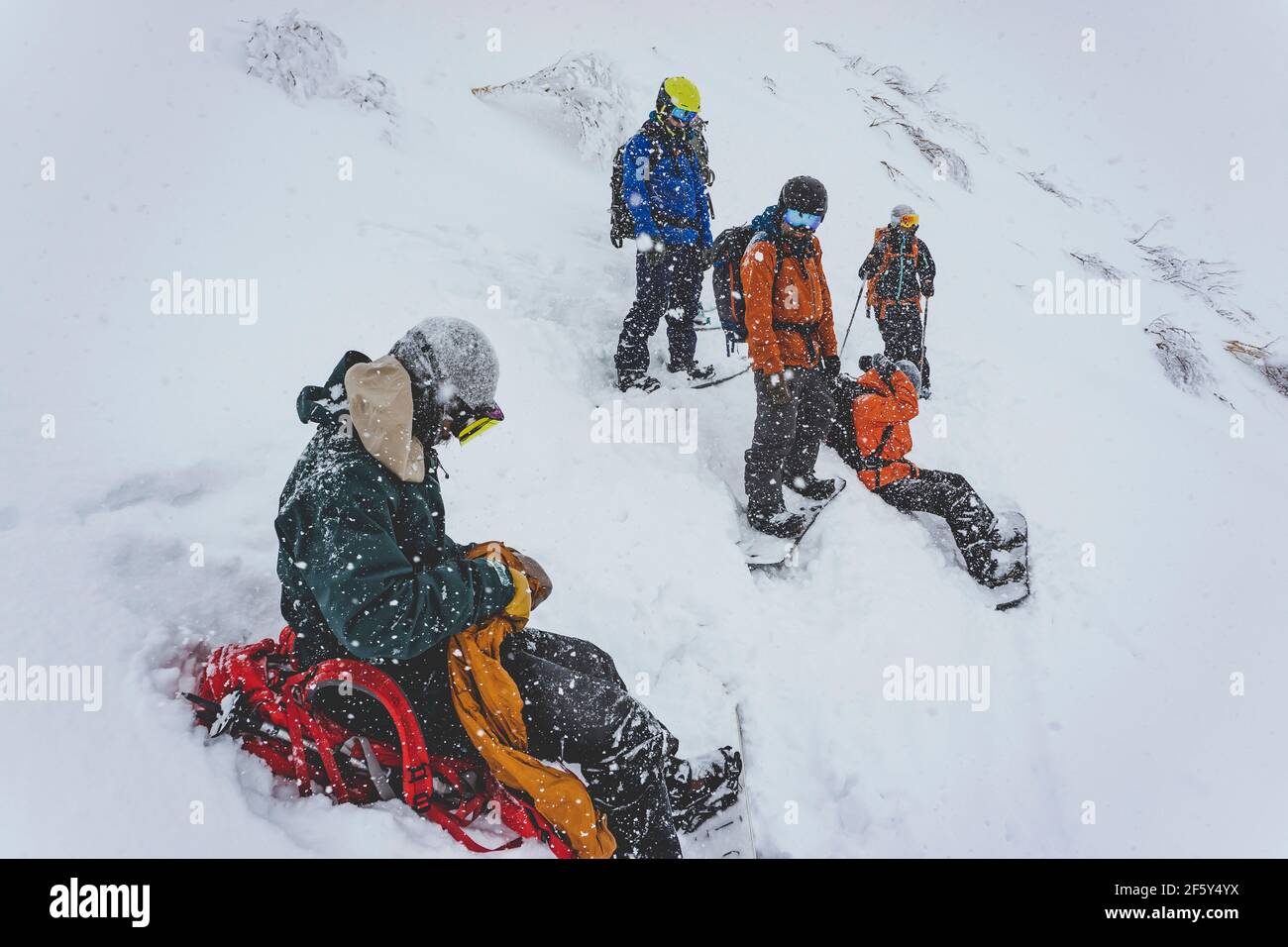 Persone con snowboard sul pendio di montagna innevata durante la nevicata Foto Stock