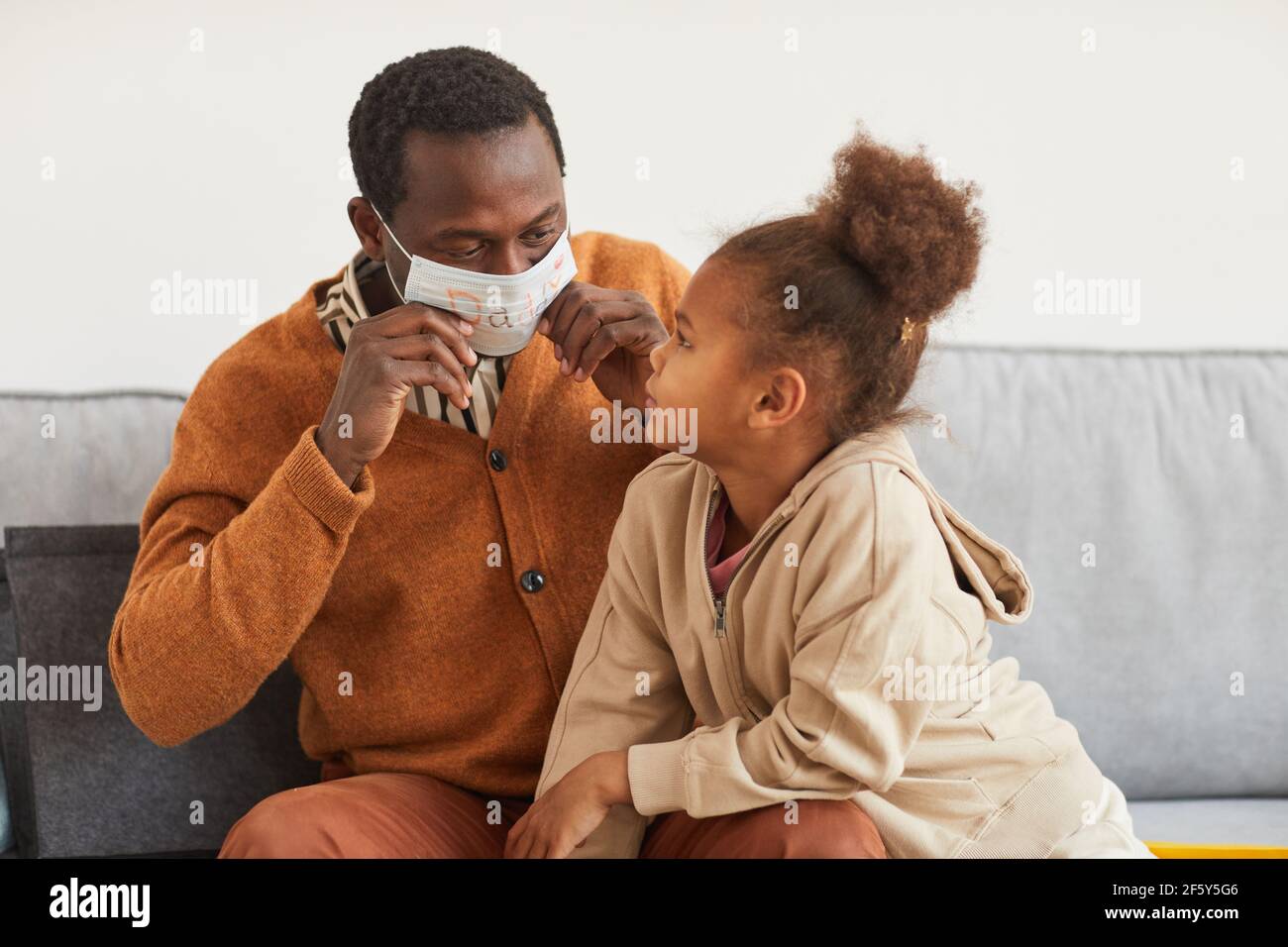 Ritratto di carina afroamericana ragazza che presenta decorata maschera viso a. Papà come dono fatto a mano per il giorno dei Padri Foto Stock