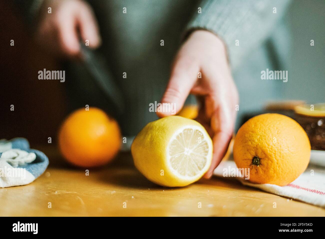 Donna anonima nella sua cucina a casa affettando arance con un sh Foto Stock