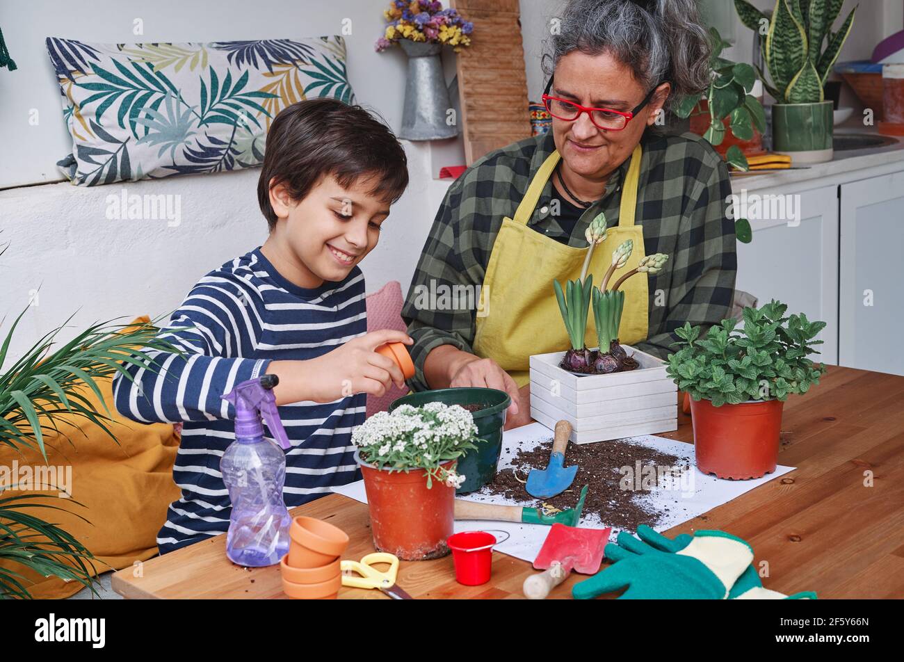 Bambino imparando con la sua madre per preparare le piante domestiche del giardino in primavera Foto Stock