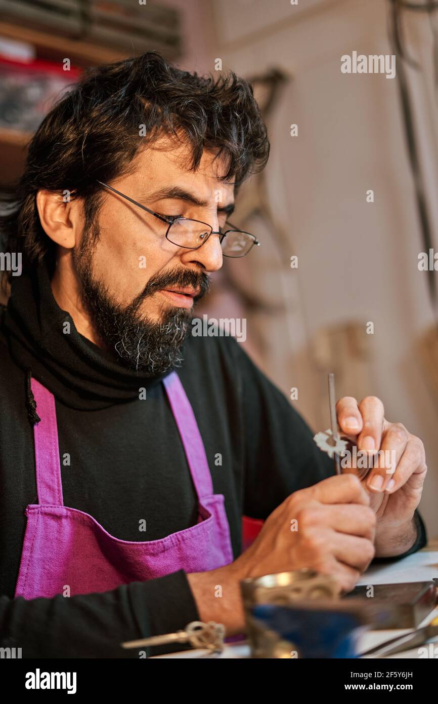 Foto verticale Jeweler artigiano che lavora al tavolo di lavoro all'interno dell'officina Foto Stock