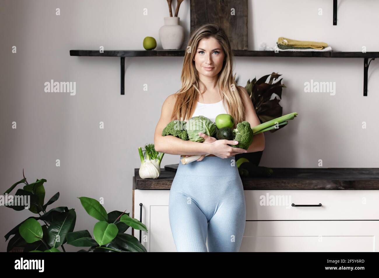 Una donna di idoneità tiene un pieno di verdure verdi grezze fresche- finocchi, broccoli, avocado, mela, porro, cavolo. Disintossicare sano cibo vegano dieta. Foto Stock