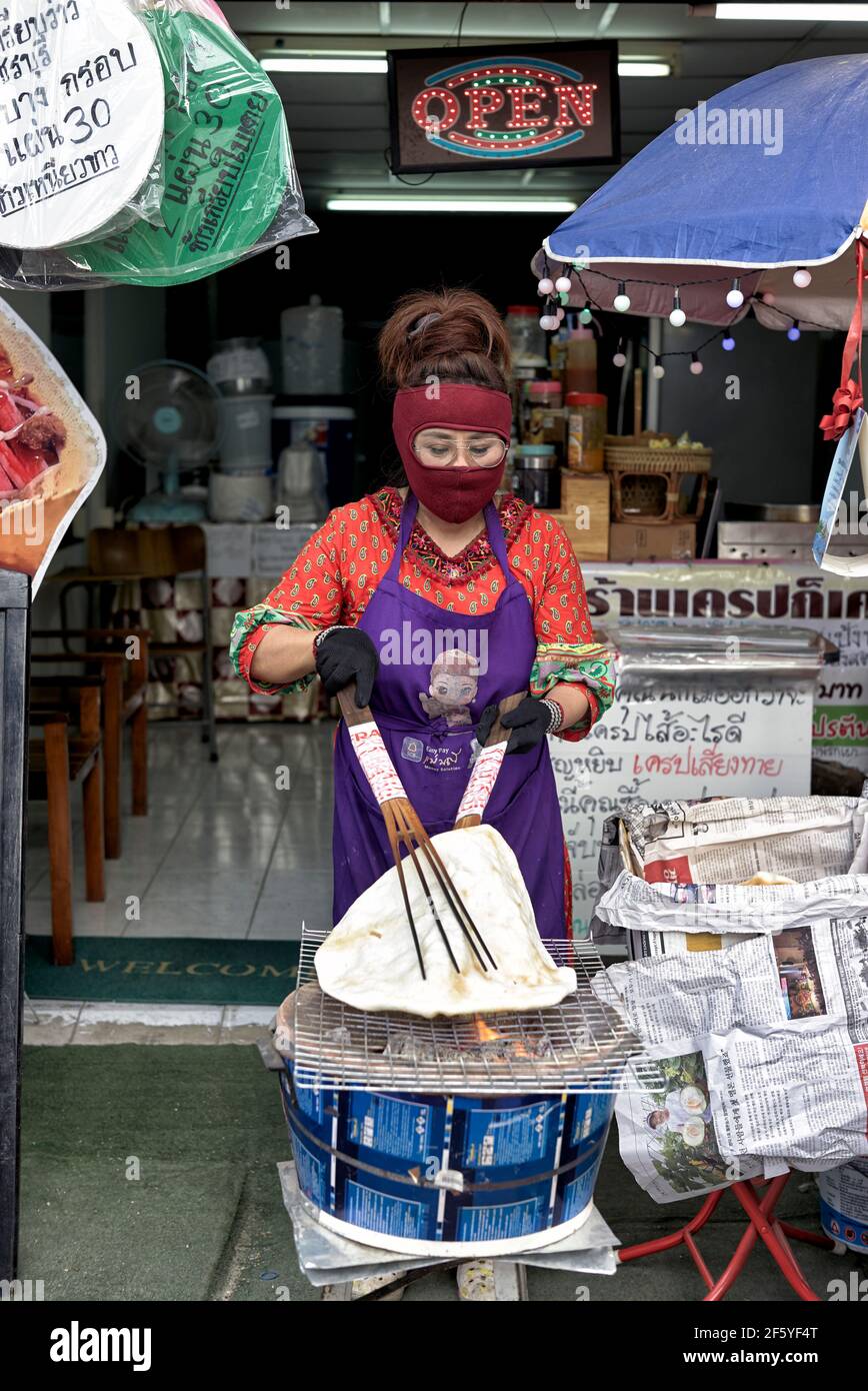 Donna che fa cuocere il papadomo su un fuoco aperto in Thailandia mercato alimentare di strada Foto Stock