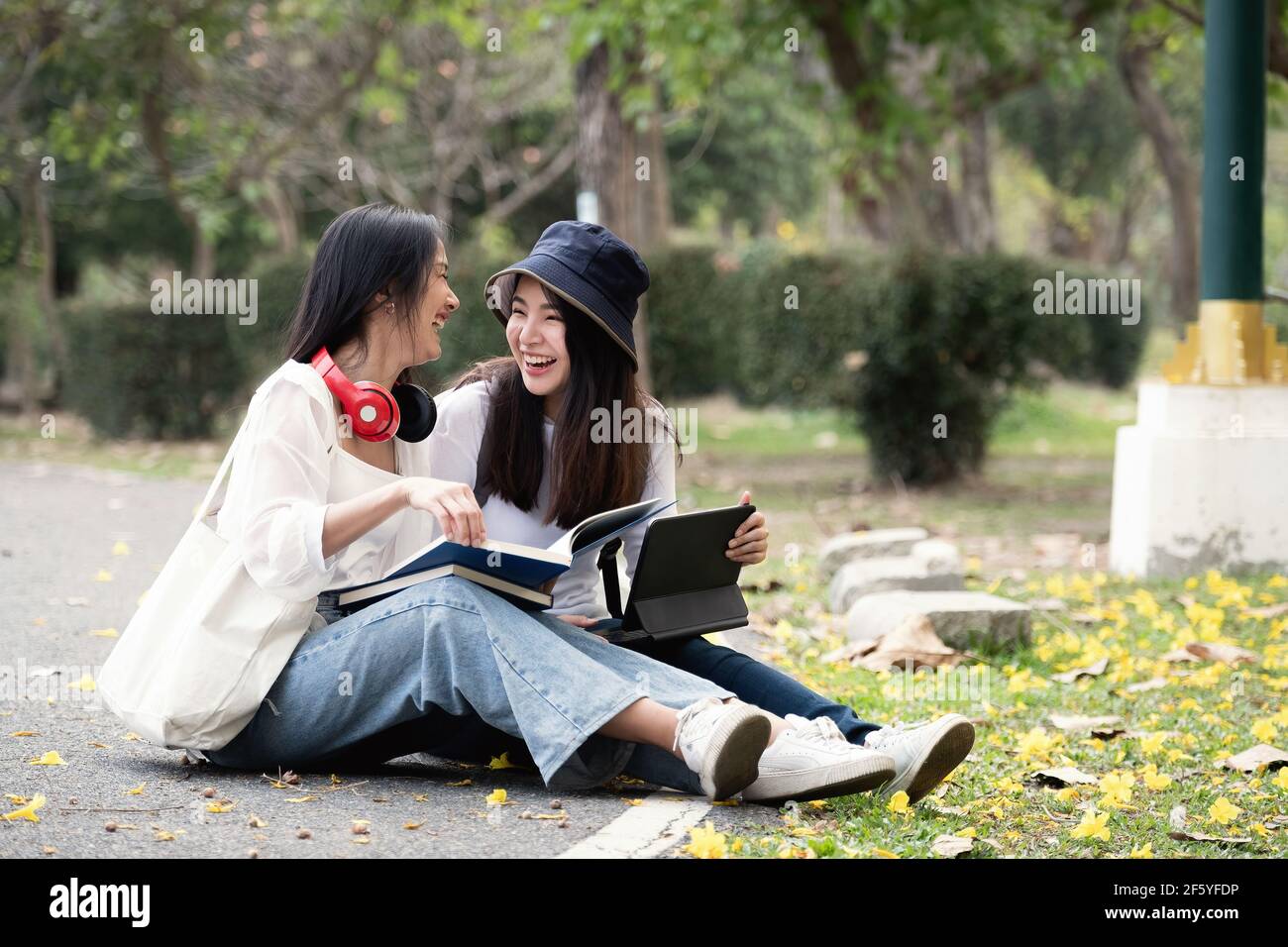 Due studenti felici che si siedono e si parlano in un campus del parco. Foto Stock