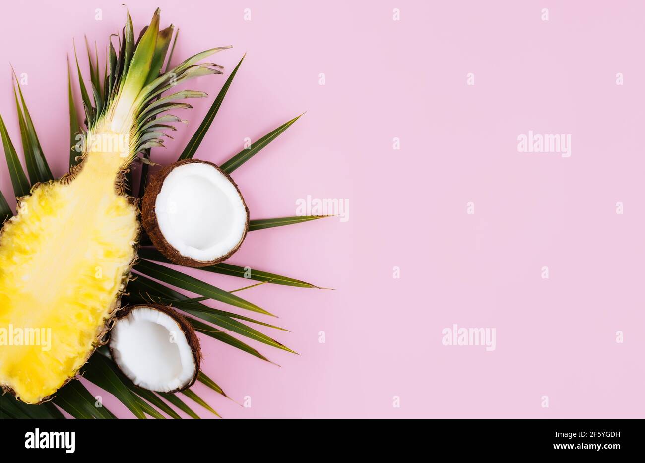 Piatto con metà tagliate di ananas fresco, cocco e foglia di palma verde su sfondo rosa pastello. Ingrediente per Pina Colada. Frutta esotica. Alta q Foto Stock