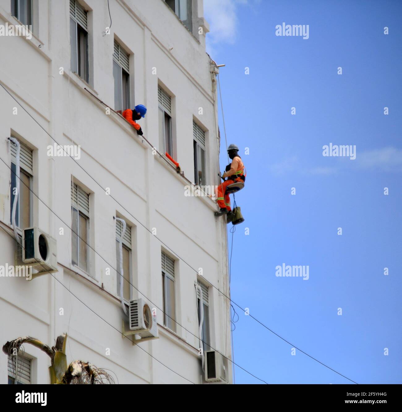 salvador, bahia, brasile - 8 gennaio 2021: Il pittore di muro è visto appeso ad una corda mentre dipinge un edificio nella città di Salvador. *** Capti locale Foto Stock