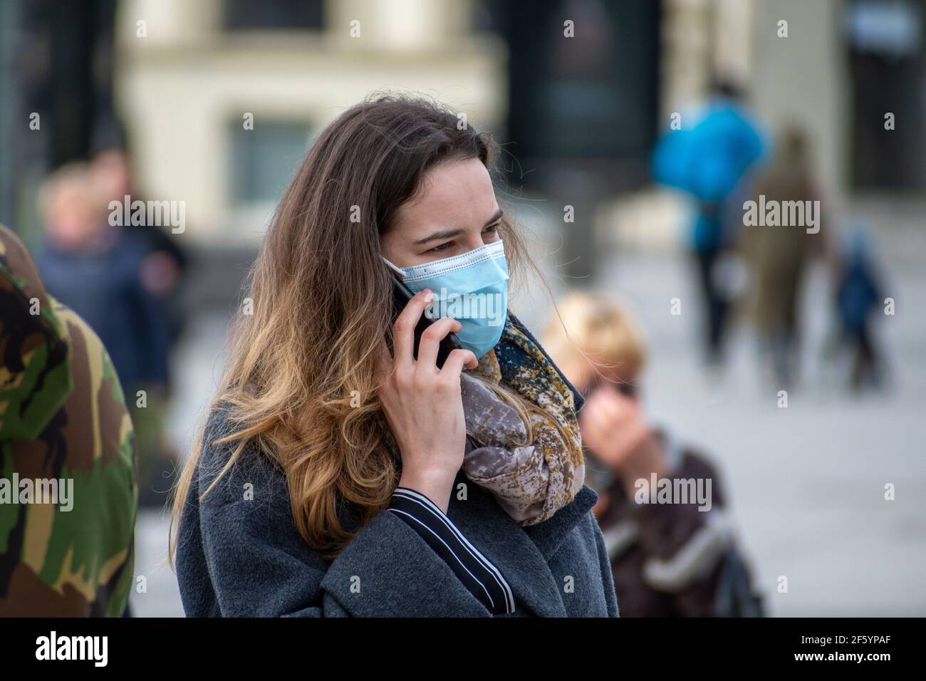 Ragazza o donna che indossa maschera e smartphone in città Durante le restrizioni di Covid o Coronavirus Foto Stock