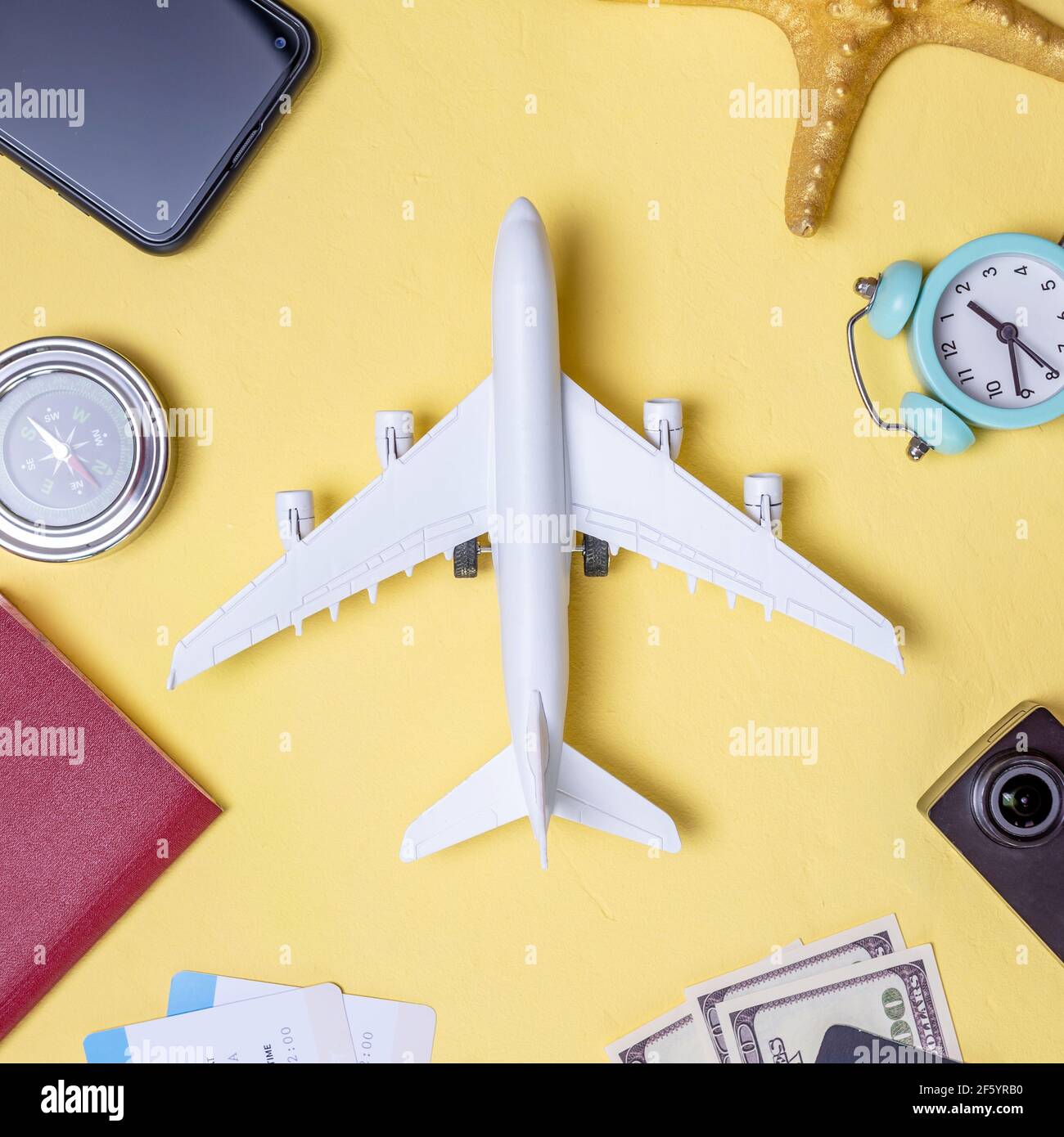 Aeroplano in miniatura e accessori da viaggio su sfondo giallo