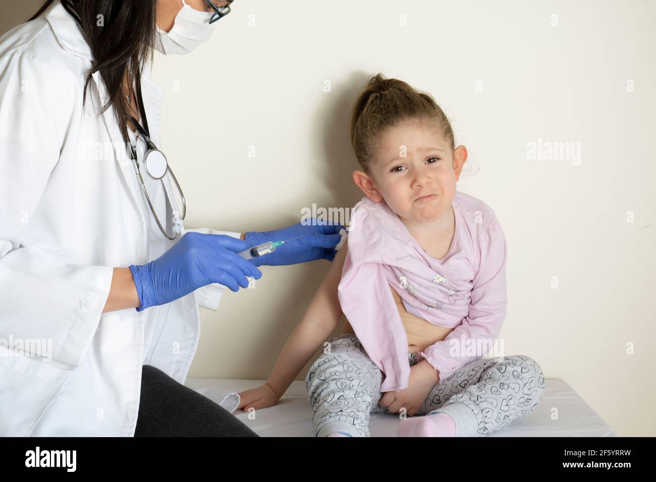 chubby bambina in esame pediatrico da parte del suo medico. vaccinato dal suo medico. Vaccino coviale selettivo per bambini Foto Stock