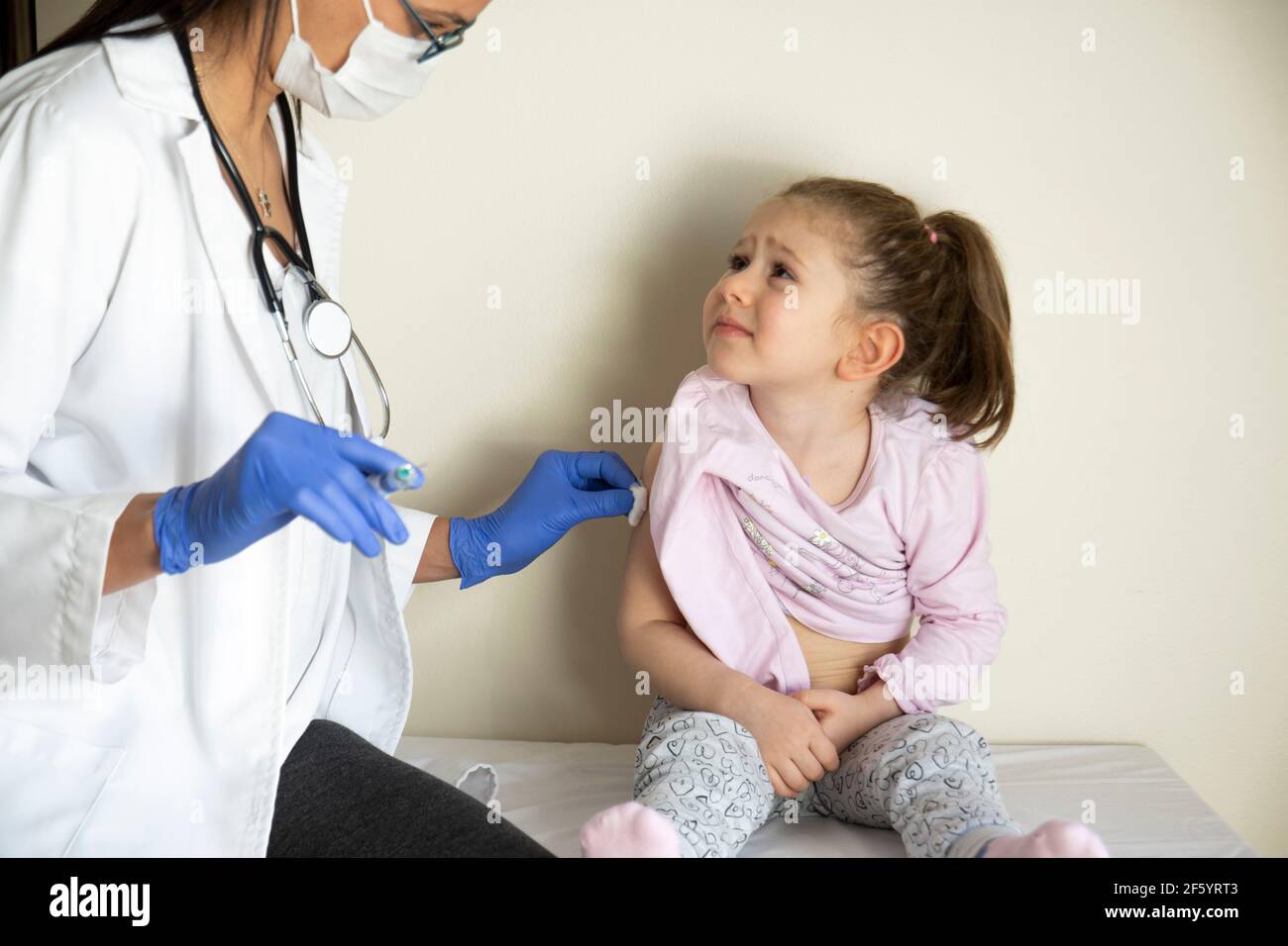 chubby bambina in esame pediatrico da parte del suo medico. vaccinato dal suo medico. Vaccino coviale selettivo per bambini Foto Stock