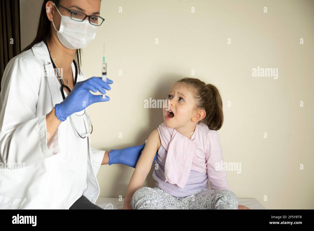 chubby bambina in esame pediatrico da parte del suo medico. vaccinato dal suo medico. Vaccino coviale selettivo per bambini Foto Stock