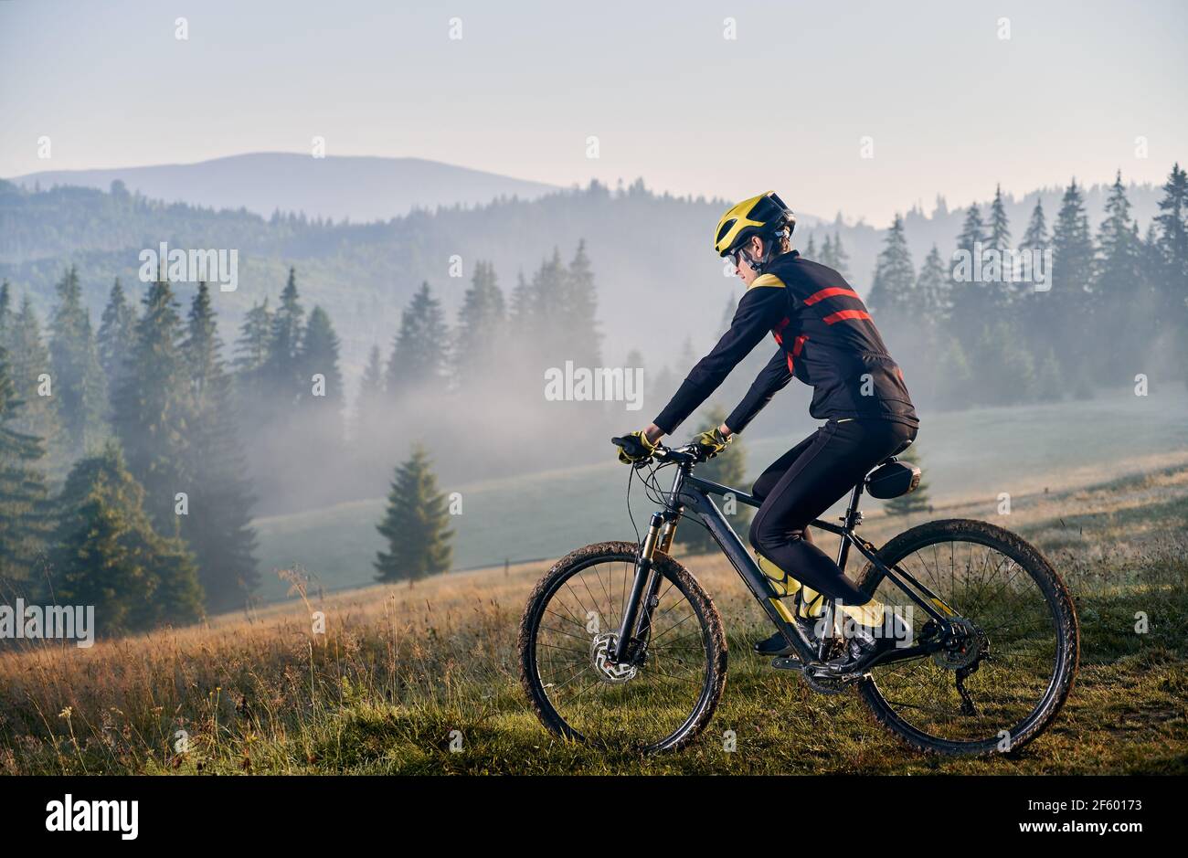 Giovane uomo in bicicletta in montagna al mattino presto Foto Stock