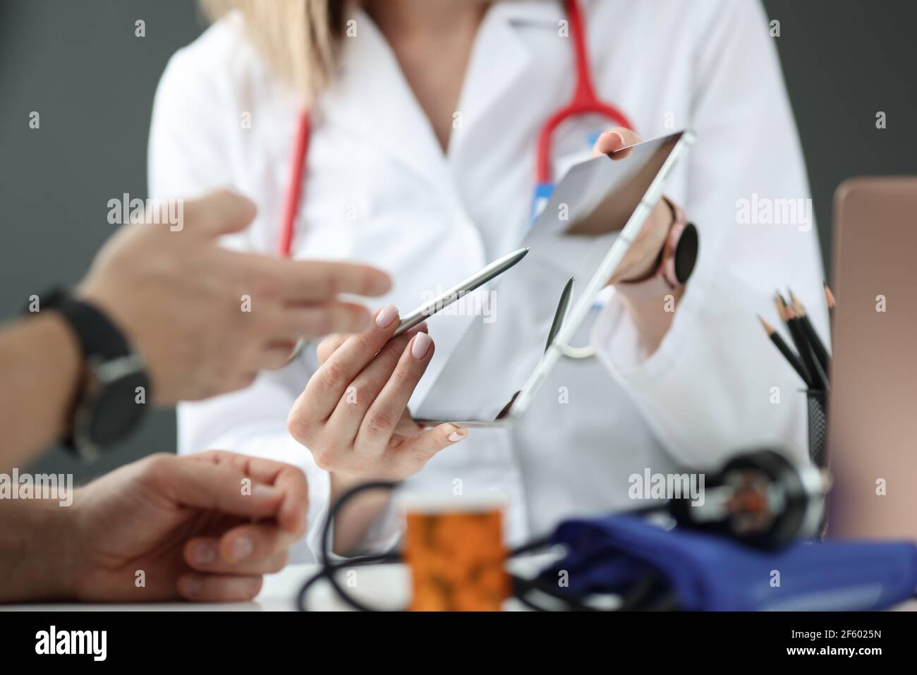 Medico che mostra i dati relativi all'esame del paziente su una compressa digitale in primo piano Foto Stock