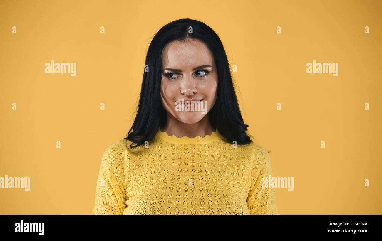 invidia, donna bruna che guarda via isolato sul giallo Foto Stock