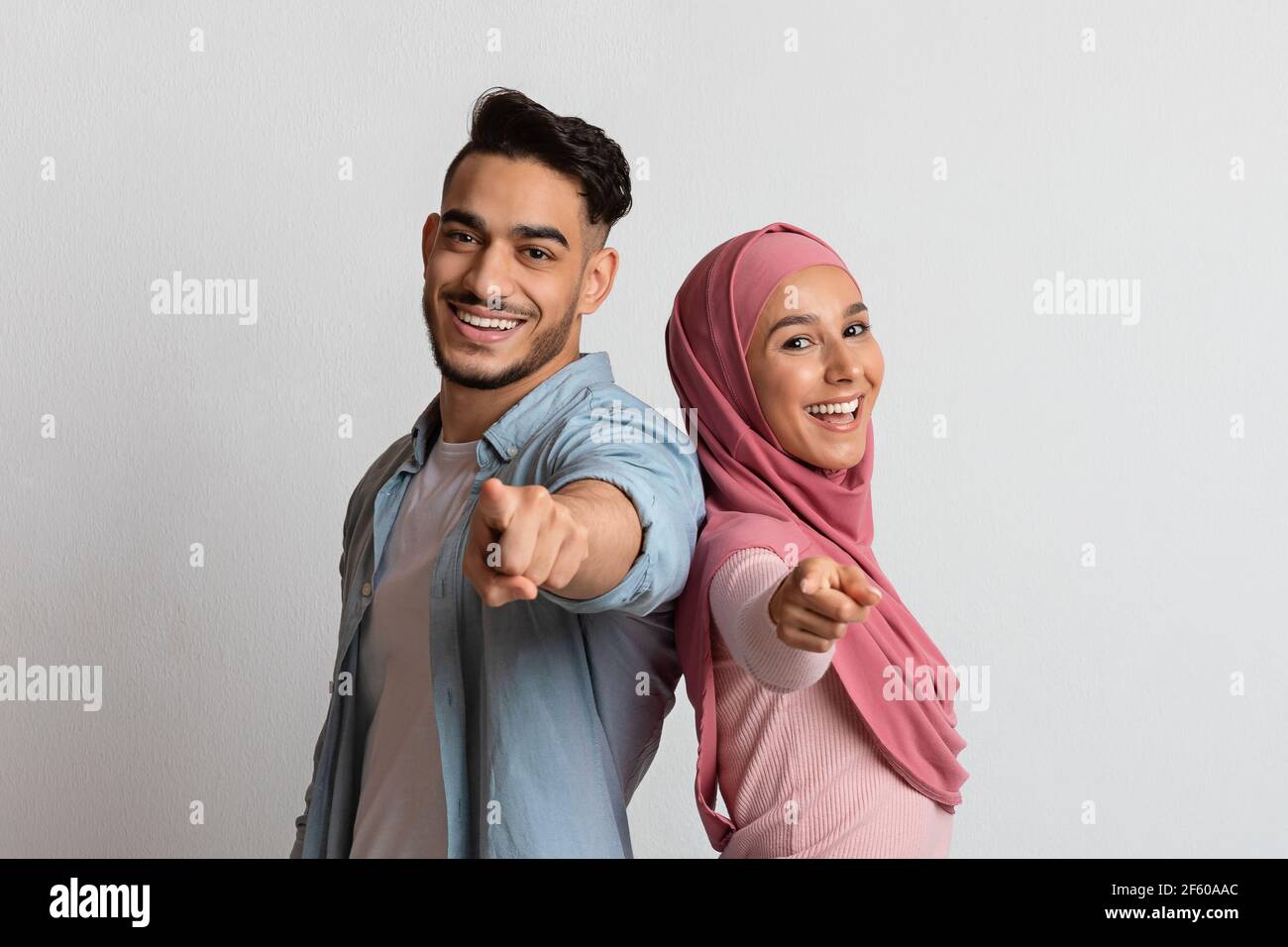 Sei il prossimo. Felice coppia musulmana che punta alla macchina fotografica e sorridente Foto Stock